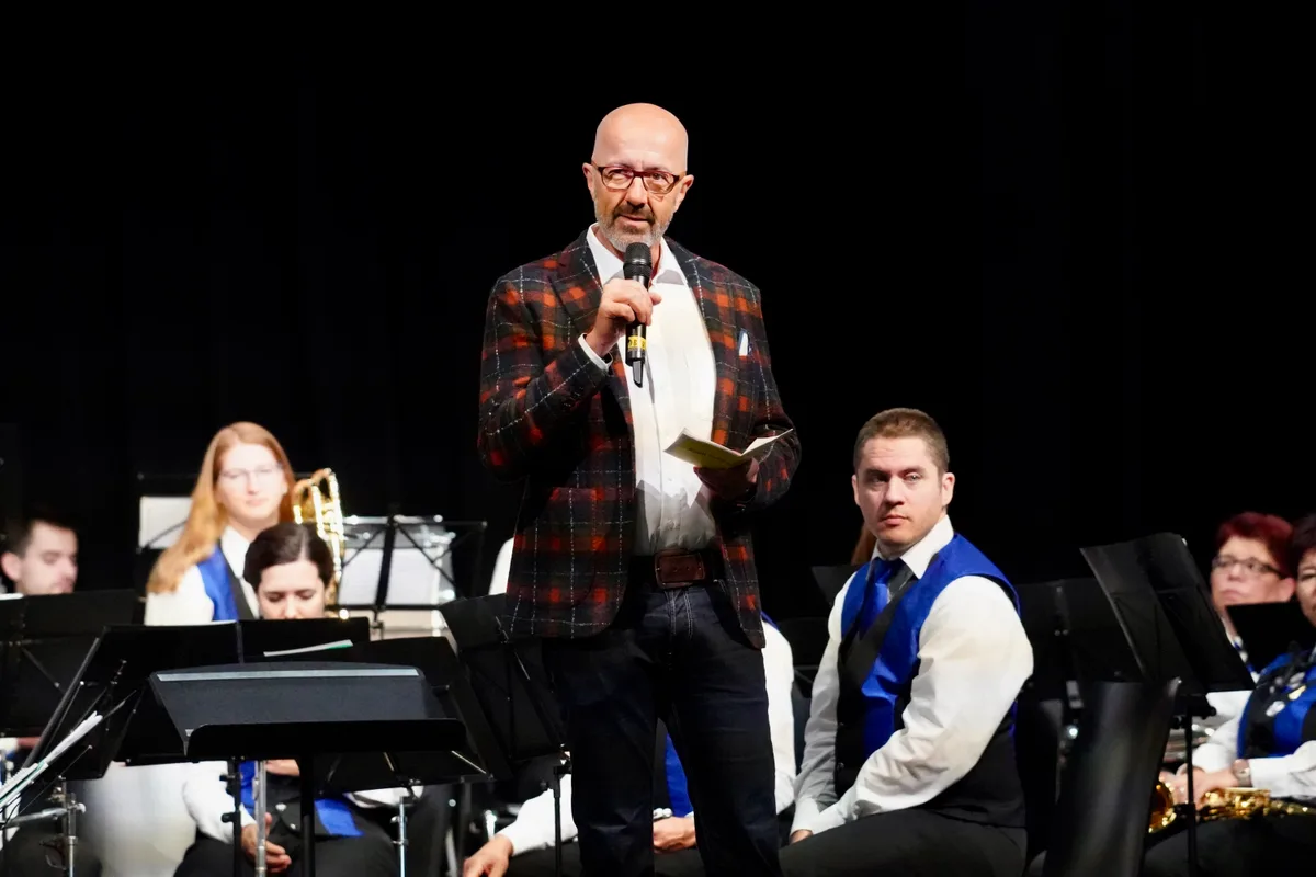 Der Dübendorfer Stadtpräsident André Ingold (SVP) hielt bei der Eröffnung eine Rede. Eine Mann in einem Karo-Anzug steht auf einer Bühne vor einem Orchester.
